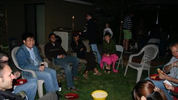 Adults and a child sit around a patio table at night with cookies and candy in view.