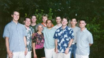 Group photo of ten people standing outside in front of trees, posing closely for a group picture.