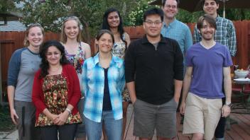  Group photo of eleven people outdoors on a wooden deck, smiling for the camera.
