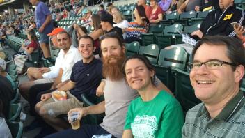 Group of people sitting in a stadium, smiling and enjoying a baseball game.