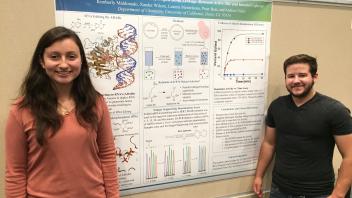 Two students standing in front of a scientific research poster presentation.