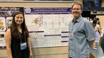 Student and faculty member standing in front of a scientific research poster.