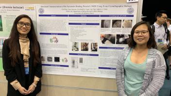 Two students stand together in front of the L194D1 protein research poster.