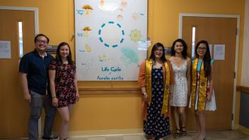 Group of five pose in front of a mural showing the life cycle of Aurelia aurita jellyfish.